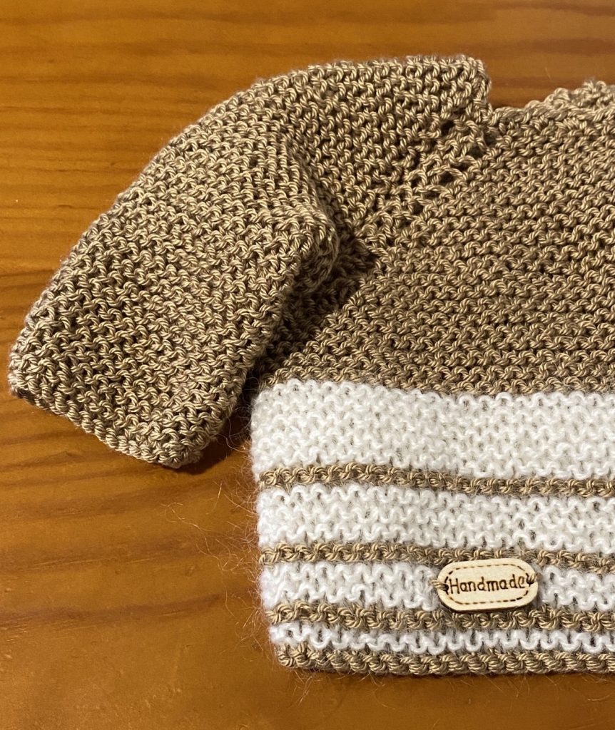Jersey infantil de punto en tonos beige y blanco, ideal como parte de ropa y complementos infantiles bordados a mano.